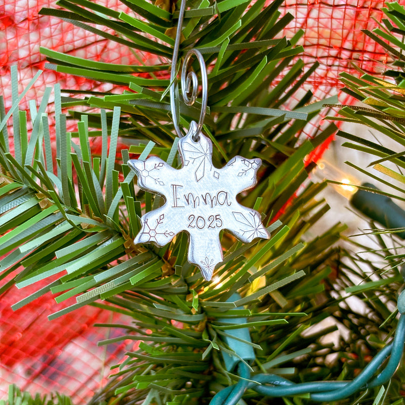 Small snowflake ornament with 1 name and date on a Christmas tree.