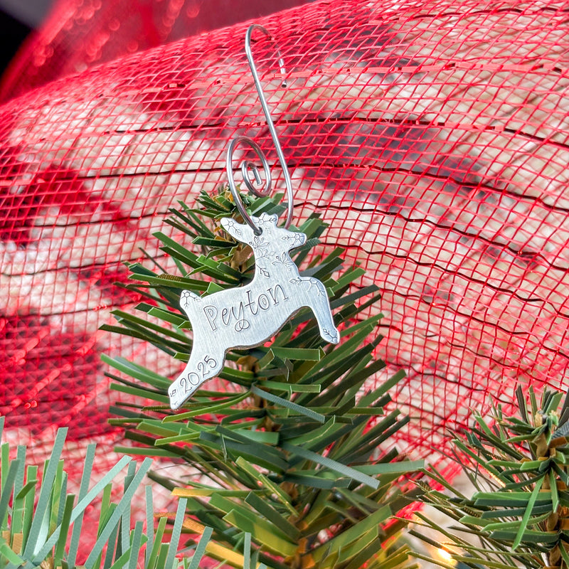 Silver reindeer ornament with 'Peyton' on a Christmas tree branch.