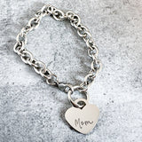 Silver chain bracelet with a heart-shaped tag on a gray surface
