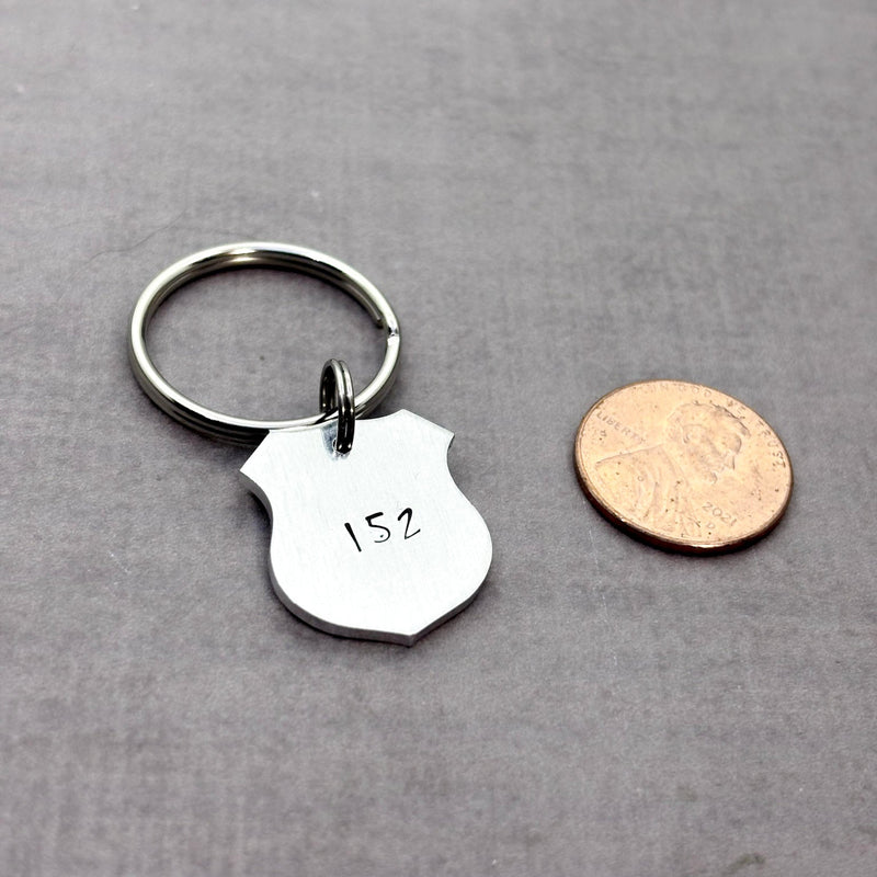 police badge key chain next to penny to show size